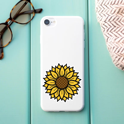 Phone case with sunflower design on a light blue surface with sunglasses and a hat.