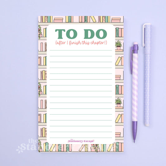 To-do list pad with book illustrations and a pen on a light purple background