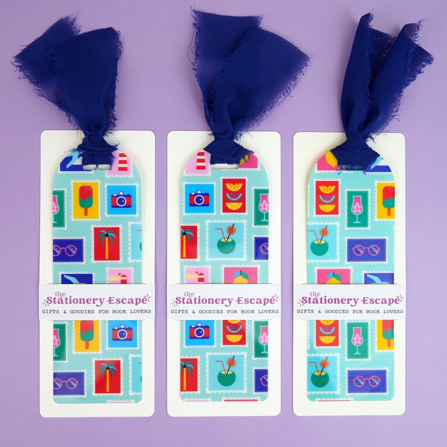 Three bookmarks with colorful designs and blue ribbons on a purple background.