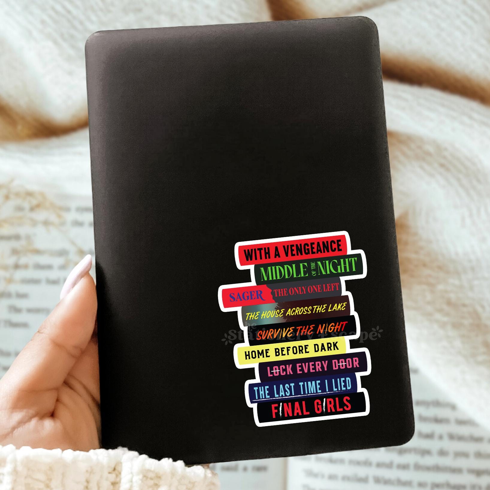 Black Kindle Case with colorful Riley Sager book stack sticker on a textured surface