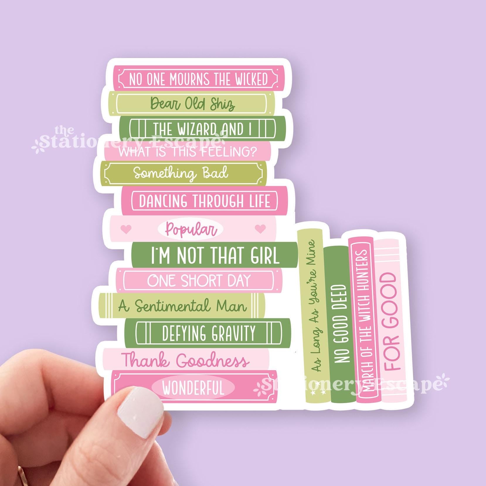 Sticker featuring stack of pink and green books with song title text held by a hand on a purple background