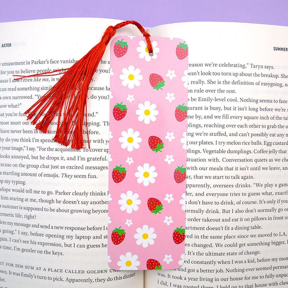 Pink bookmark with strawberry and daisy pattern on an open book