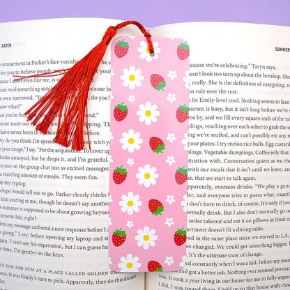 Pink bookmark with strawberry and daisy pattern on an open book