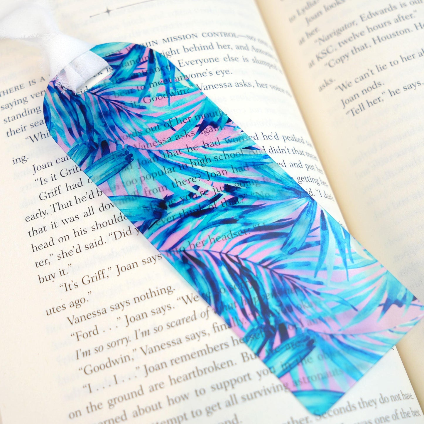 Colorful bookmark with blue and pink palm leaf pattern on an open book