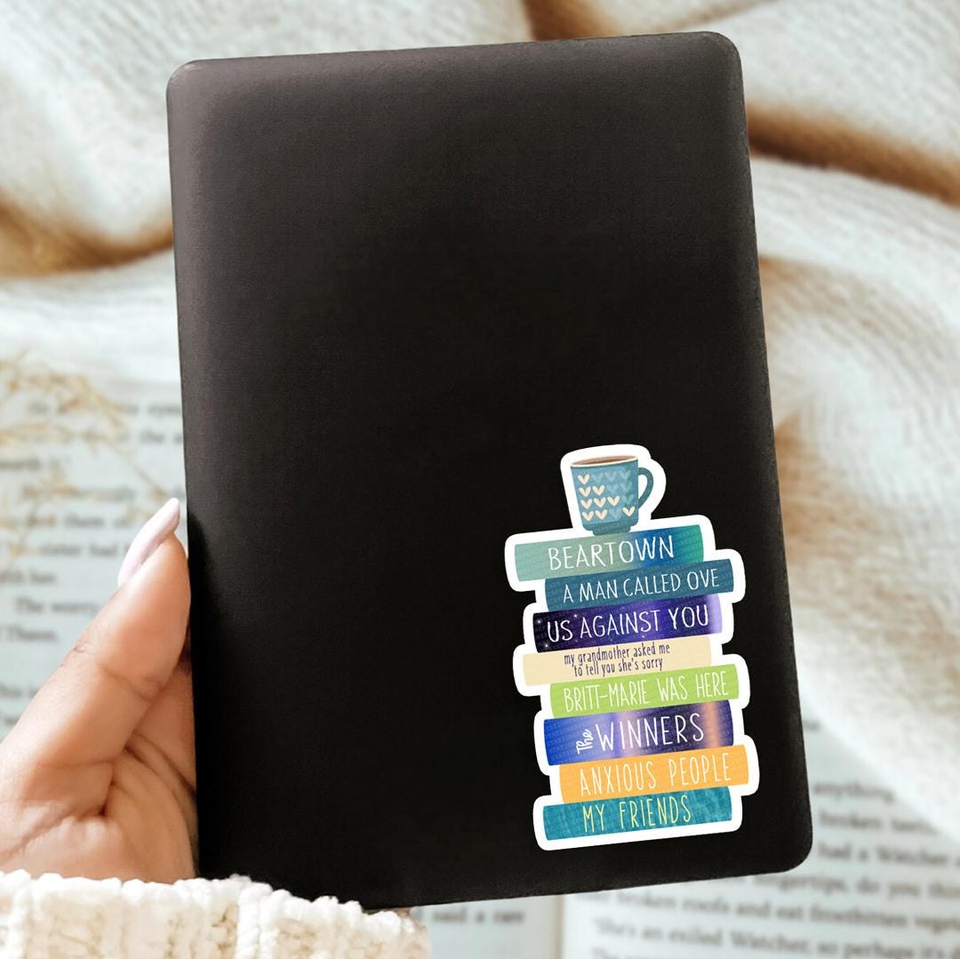 Black Kindle case with colorful Fredrik Backman sticker design held by a hand on a textured surface