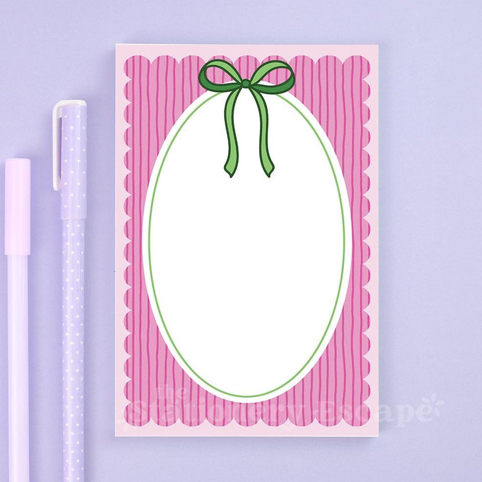 Notepad with pink border and green bow on a purple background