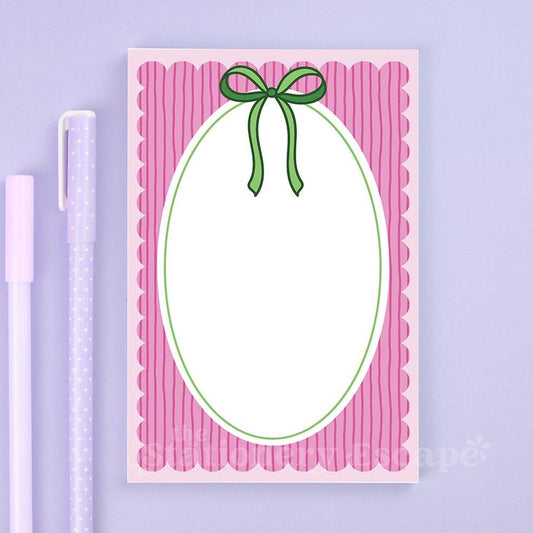 Notepad with pink border and green bow on a purple background