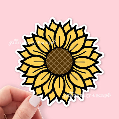 Sunflower sticker held by a hand on a pink background with 'The Stationery Escape' branding.