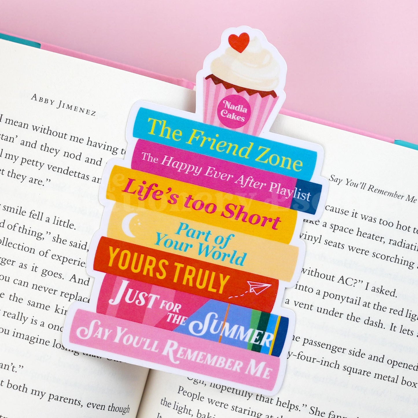 Die-cut book stack bookmark featuring colorful book spines and titles by Abby Jimenez topped with a cupcake