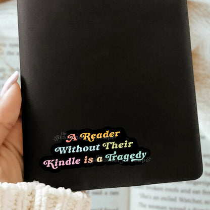 Black Kindle case with colorful text sticker "A Reader Without Their Kindle is a Tragedy" held by a hand
