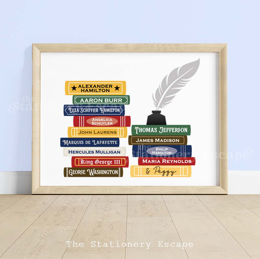 Framed book stack art print featuring spines with names of historical revolutionary-era figures such as Alexander Hamilton and Thomas Jefferson. The book stack is topped with an inkwell and feather quill pen. 
