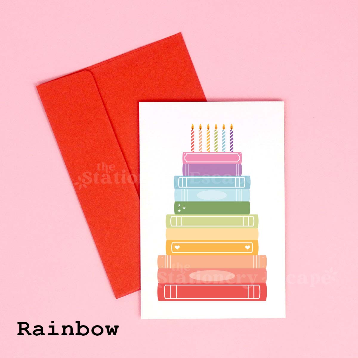 Colorful birthday card featuring a "birthday cake" made from rainbow stacked books on a pink background with a red envelope