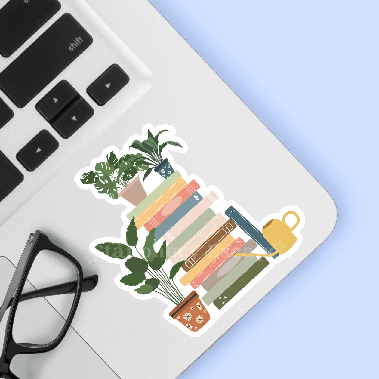 Sticker of books and plants on a laptop keyboard with glasses nearby