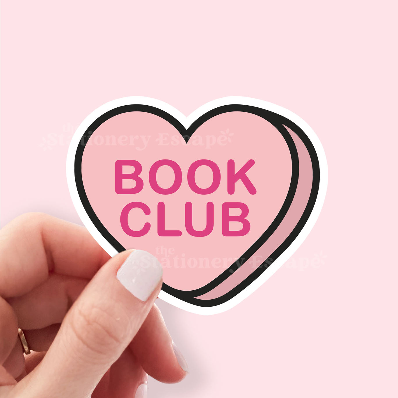 Heart-shaped 'Book Club' sticker held by a hand on a pink background