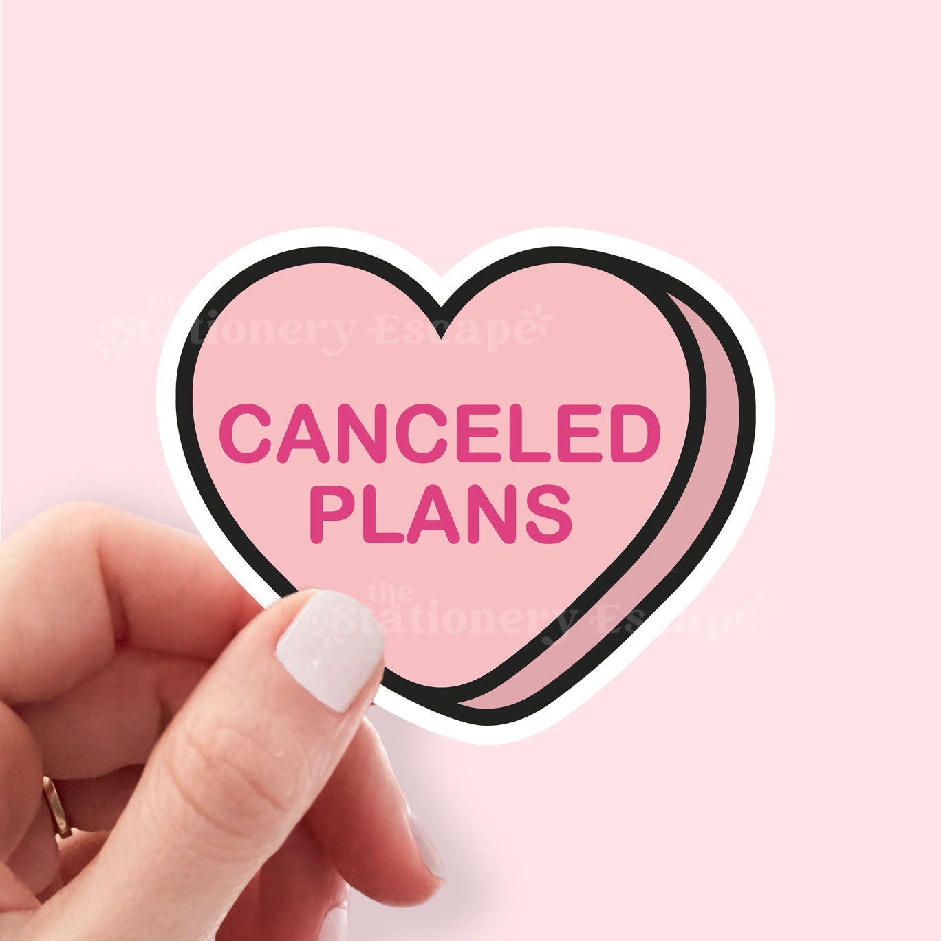 Heart-shaped sticker with 'Canceled Plans' text held by a hand on a pink background