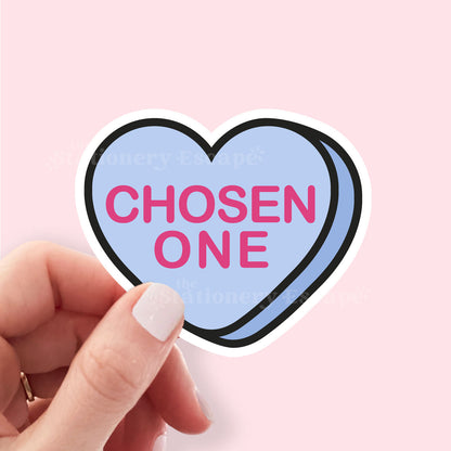 Heart-shaped sticker with 'Chosen ONE' text held by a hand against a pink background
