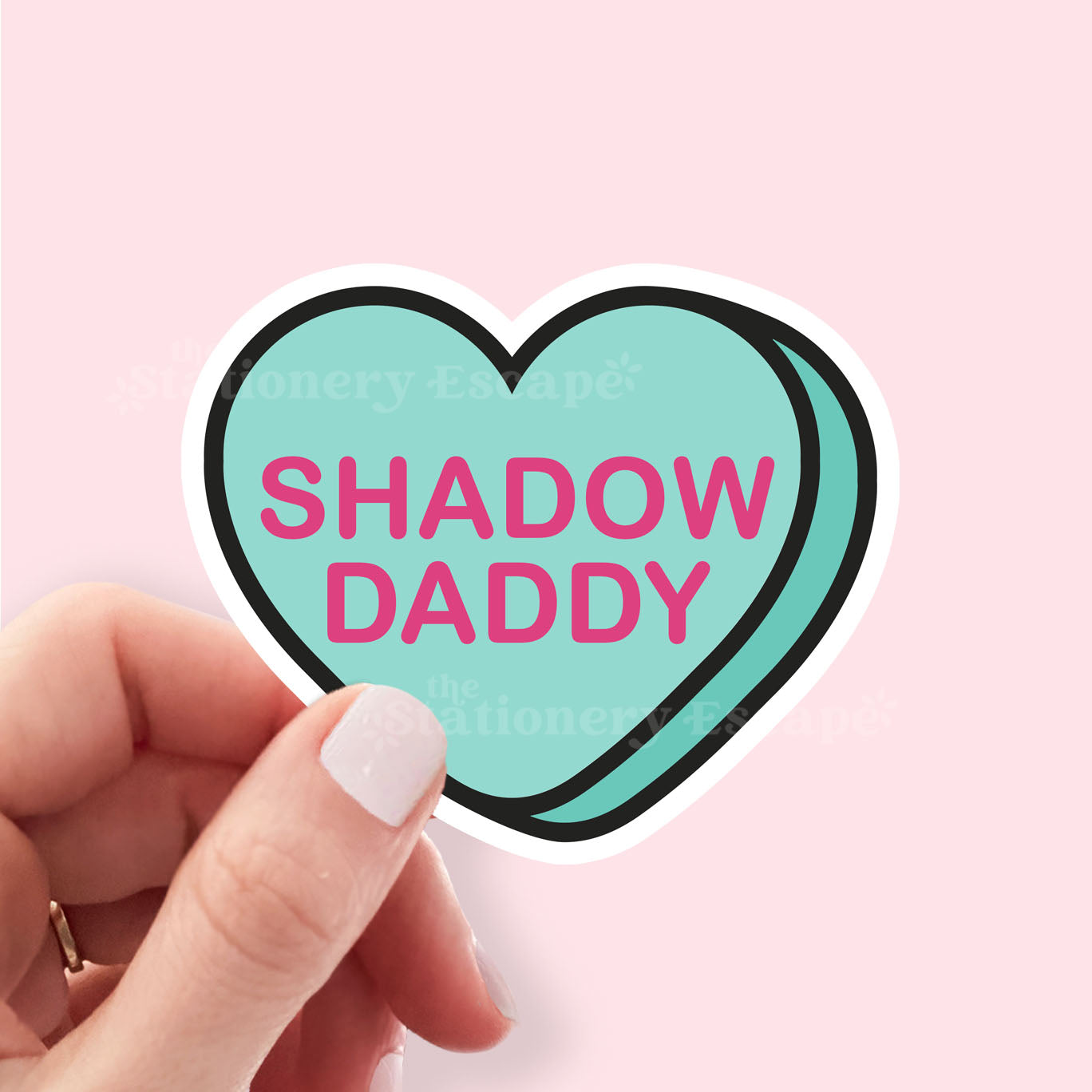 Heart-shaped sticker with 'SHADOW DADDY' text held by a hand on a pink background