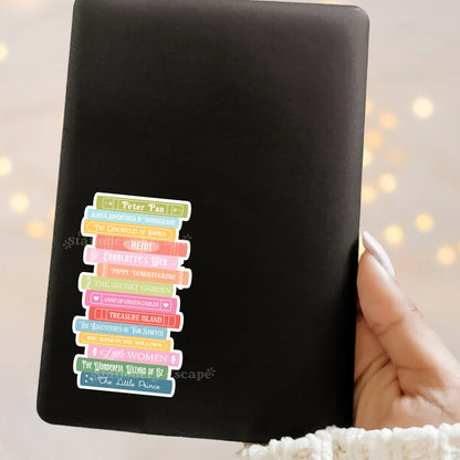 Black Kindle with colorful book spine designs held by a hand against a blurred light background