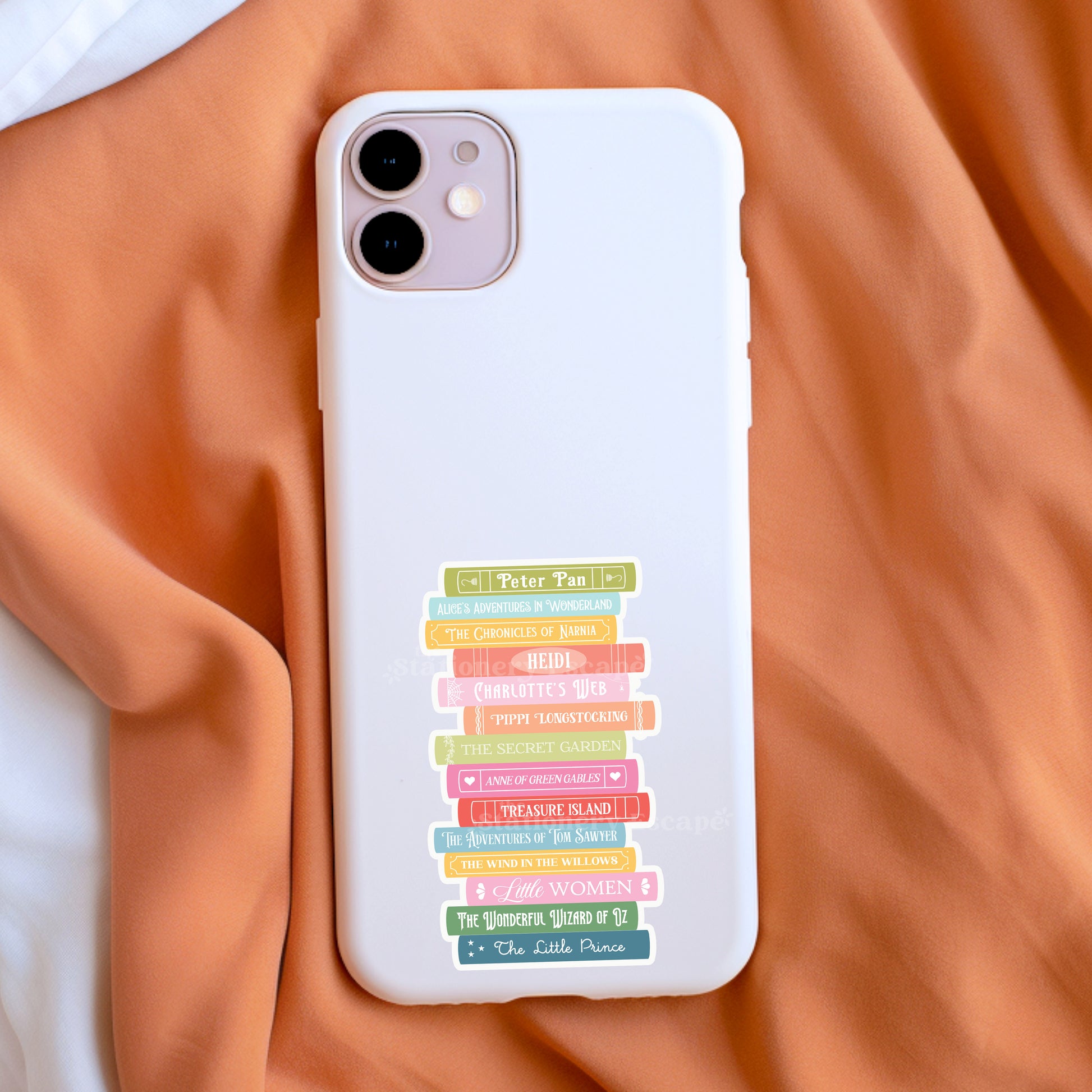White phone case with colorful book stack sticker on an orange fabric background