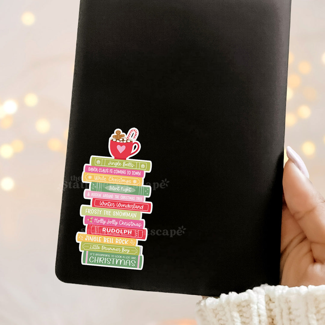 Kindle with colorful Christmas-themed book stack sticker on a blurred light background