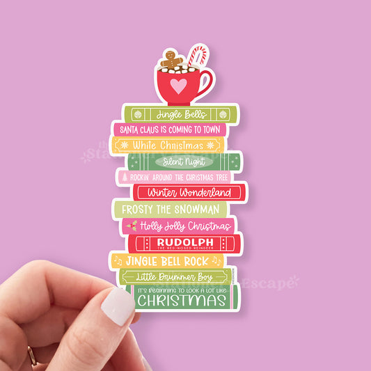 Stack of Christmas-themed books with a mug on top against a pink background