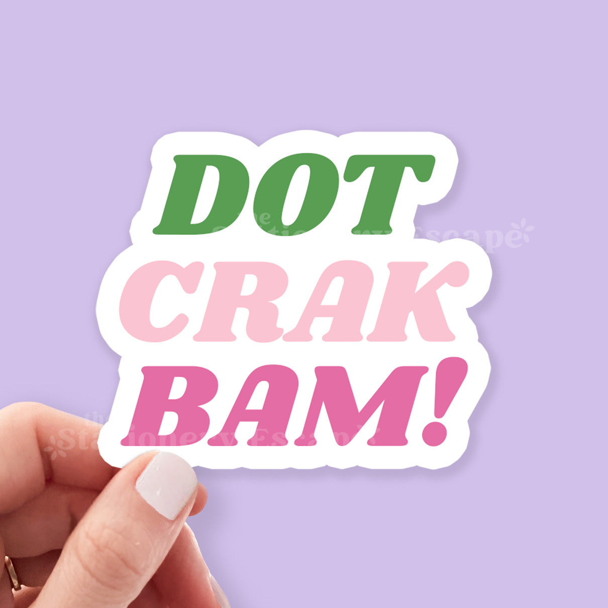 Hand holding a sticker with 'DOT CRAK BAM!' text on a purple background