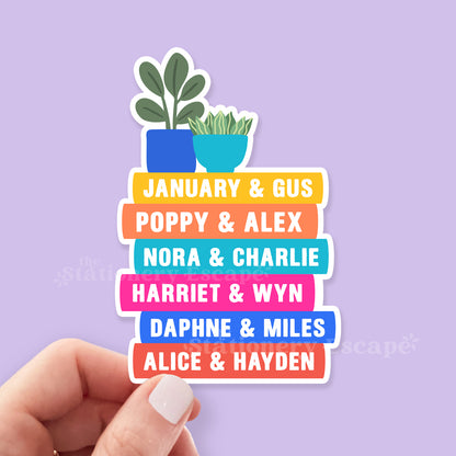 Stack of colorful Emily Henry book spines on a sticker held by a hand on a purple background