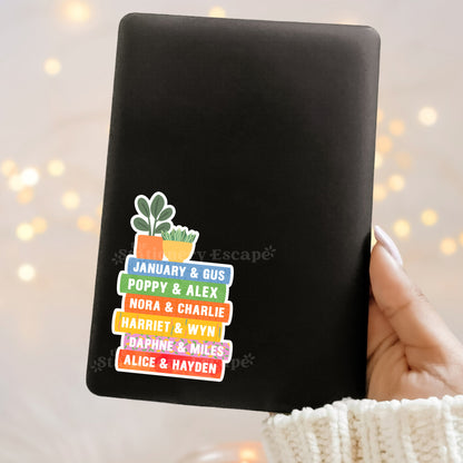 Black Kindle case with colorful Emily Henry book stack and plant design sticker on a blurred light background