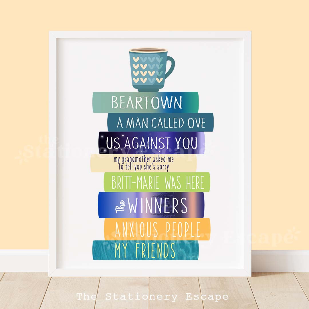 Framed colorful book stack art print featuring the spines and titles of literary novels by Fredrik Backman. The book stack is topped by a heart-decorated mug of coffee.