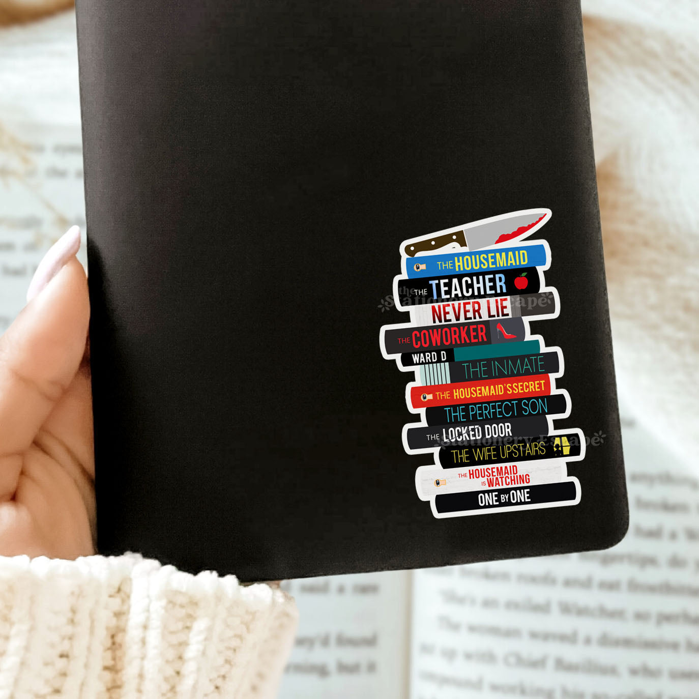 Black Kindle case with a colorful Freida McFadden book stack sticker on a white surface
