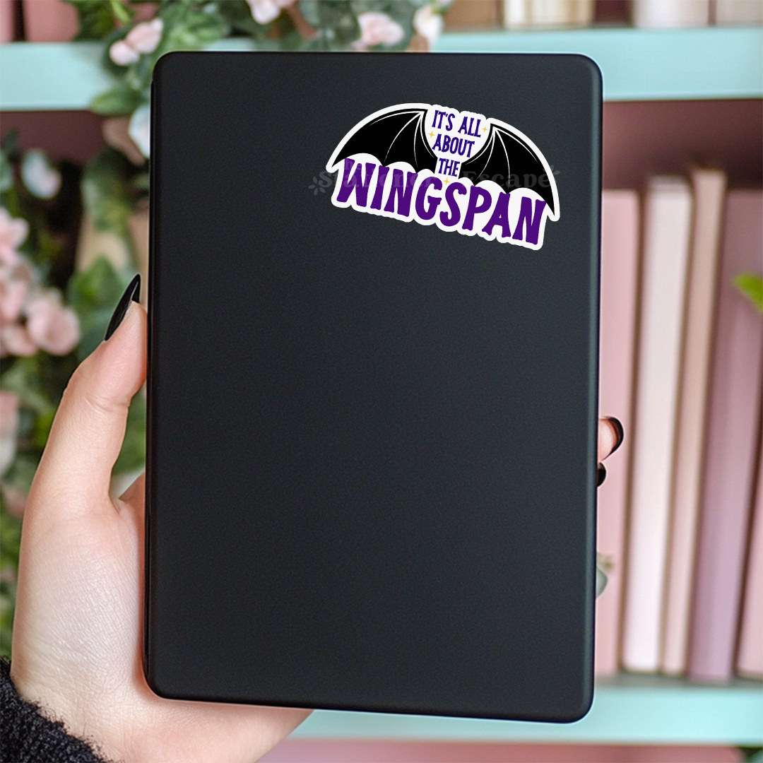 Black Kindle case with 'It's All About The Wingspan' sticker held by a hand.