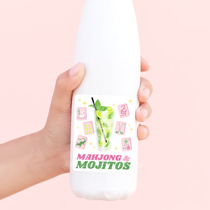 Hand holding a white water bottle with 'Mahjong & Mojitos' design on a pink background