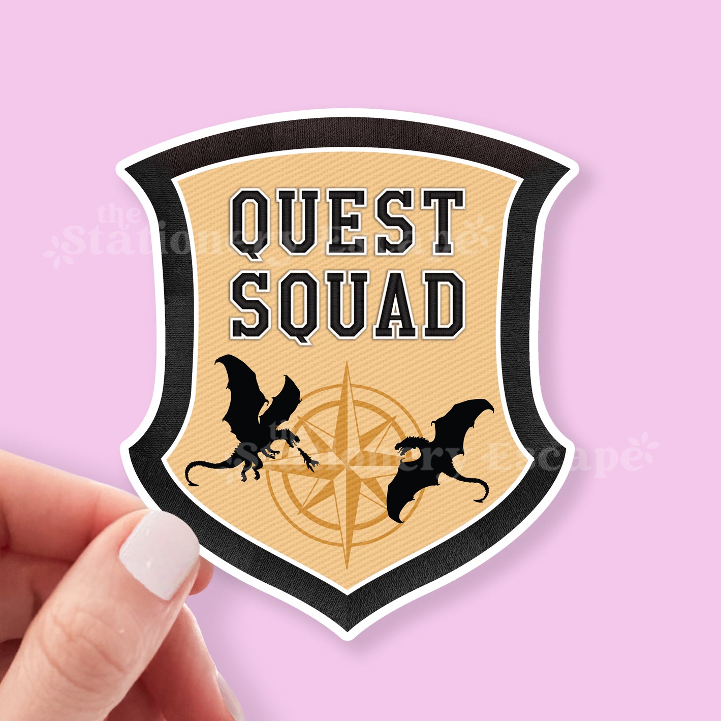 Shield-shaped sticker with 'Quest Squad' text and dragons on a pink background