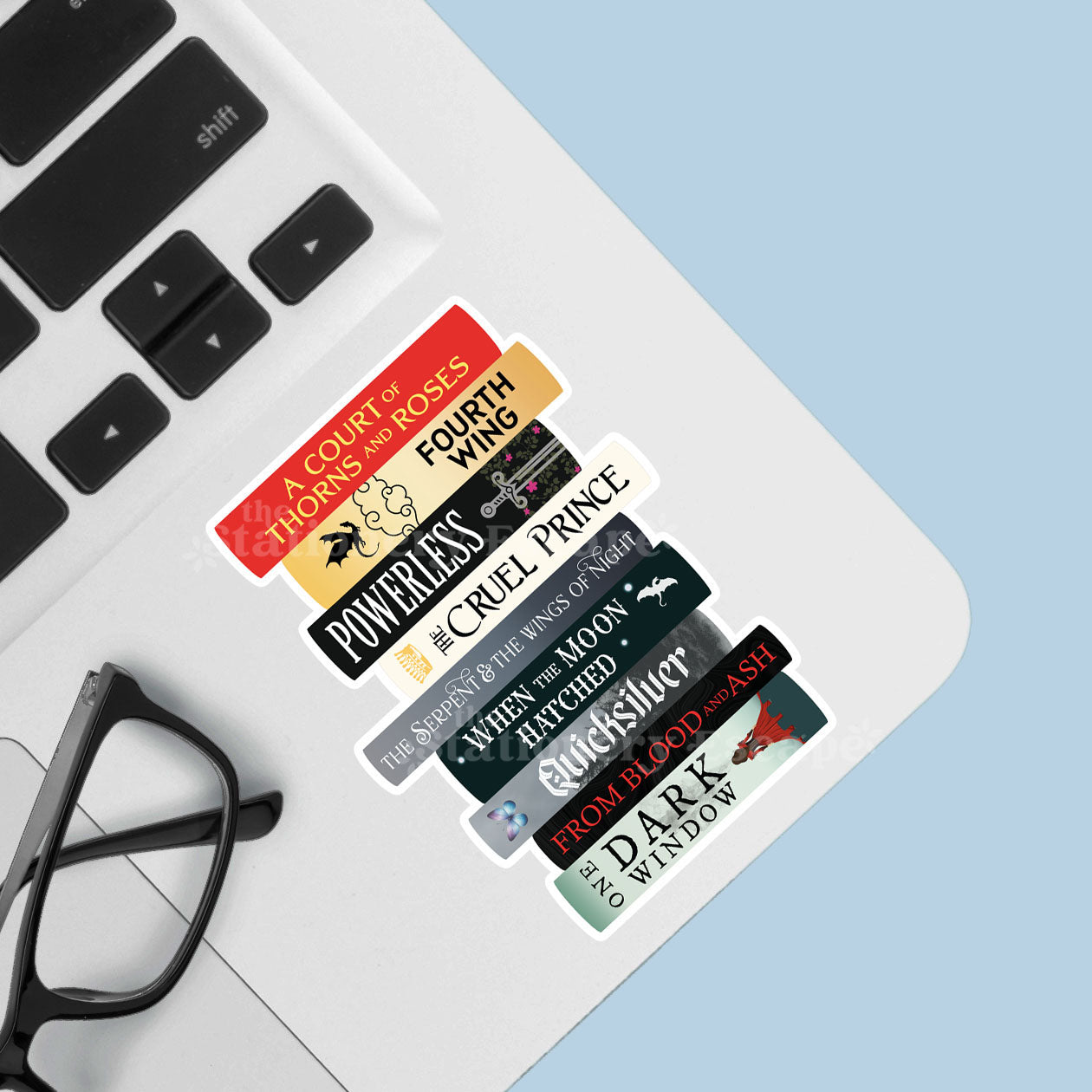 Romantasy book stack sticker with book titles on a laptop keyboard