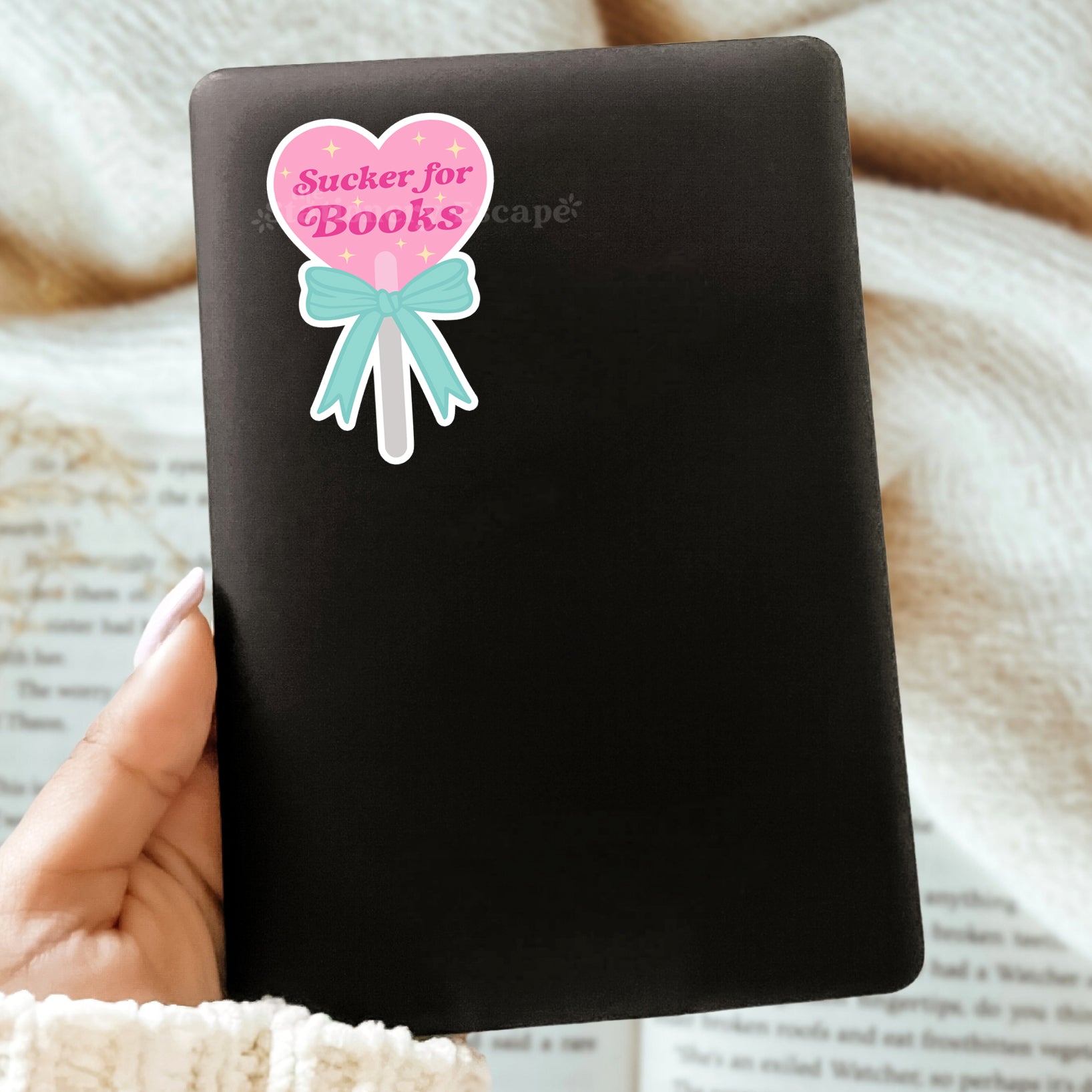 Black Kindle case with a decorative sticker featuring a heart-shaped lollipop and the words "Sucker for Books"