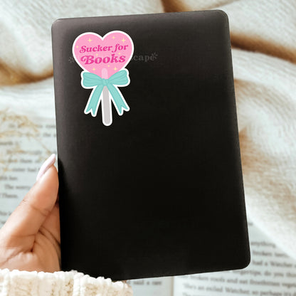 Black Kindle case with a decorative sticker featuring a heart-shaped lollipop and the words "Sucker for Books"