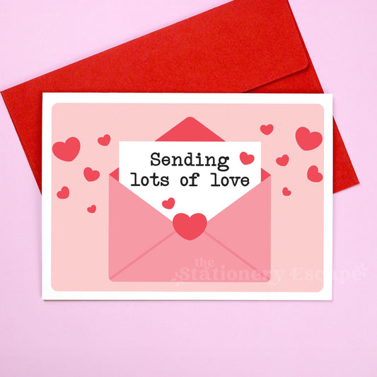 Card with 'Sending lots of love' text and red hearts on a pink background with a red envelope.