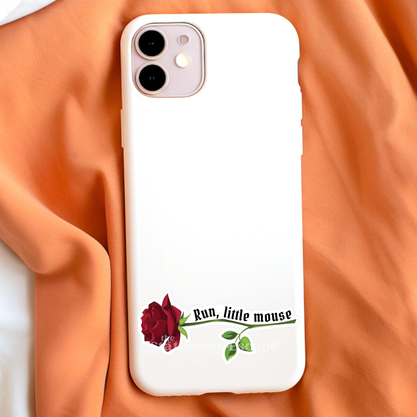 Phone case with a rose design and text on an orange fabric background