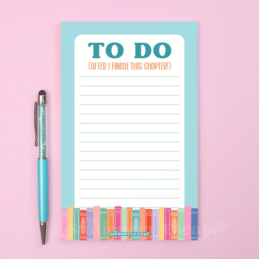 Notepad with 'To Do' list and blue border with colorful books and pen on a pink background